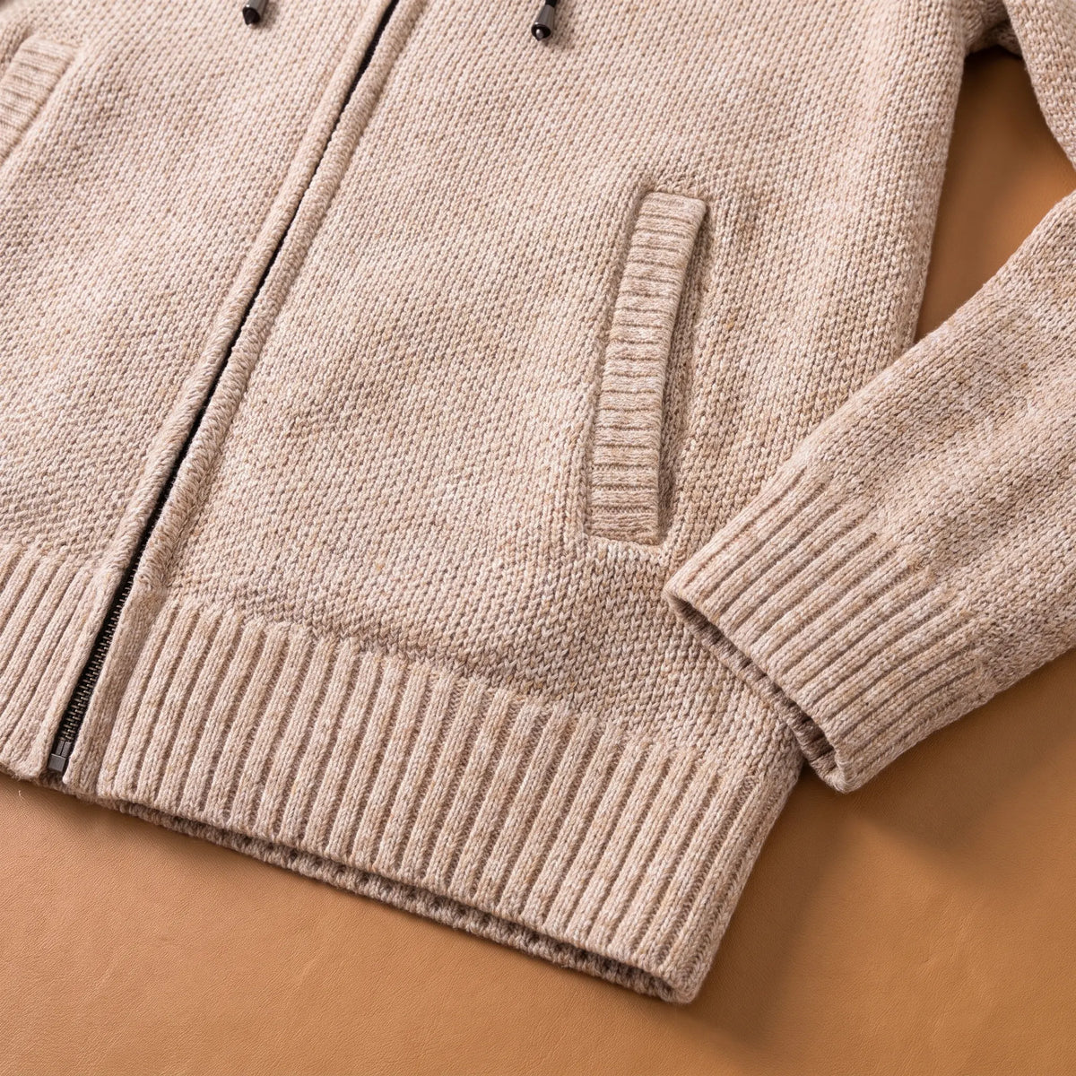 Close-up of the beige marled knit hoodie side pocket, ribbed hem and cuff