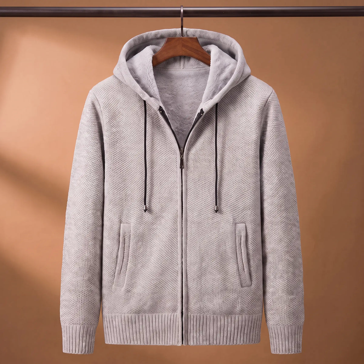 Marled knit hoodie in light grey with fleece-lined hood on a wooden hanger