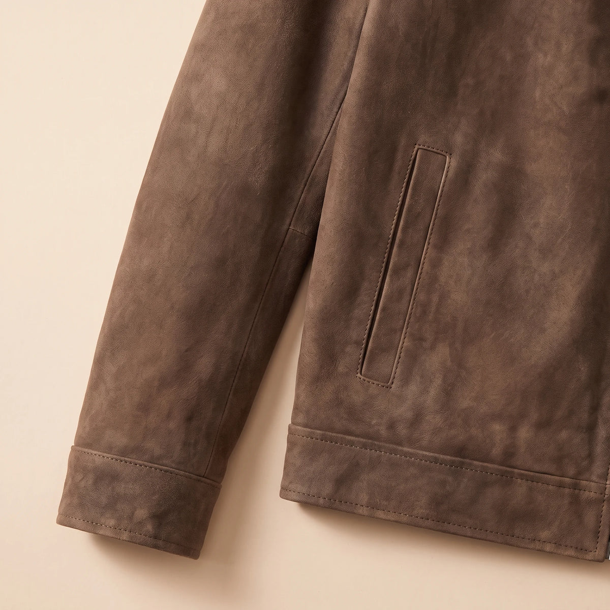 Close up of the cuff, hem and welt pocket on the matte finish jacket
