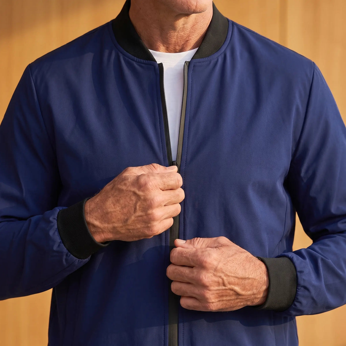 Man zipping up the MATTE SHELL BOMBER, close view of the front closure