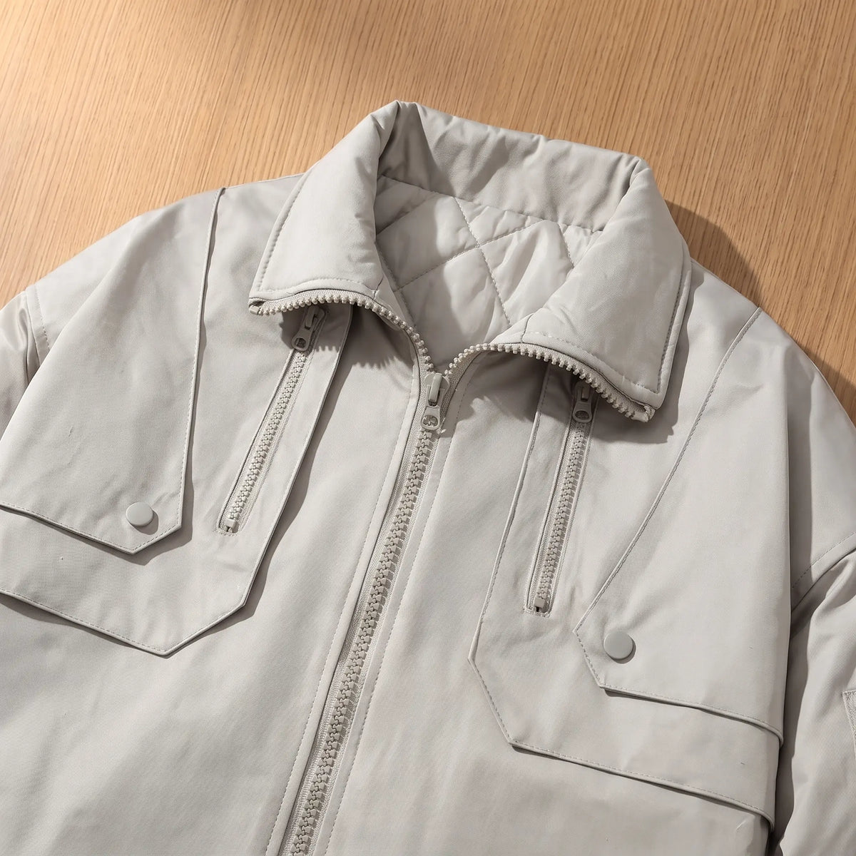 Close up of the PADDED COLLAR JACKET collar, chest zip pockets and snap flap