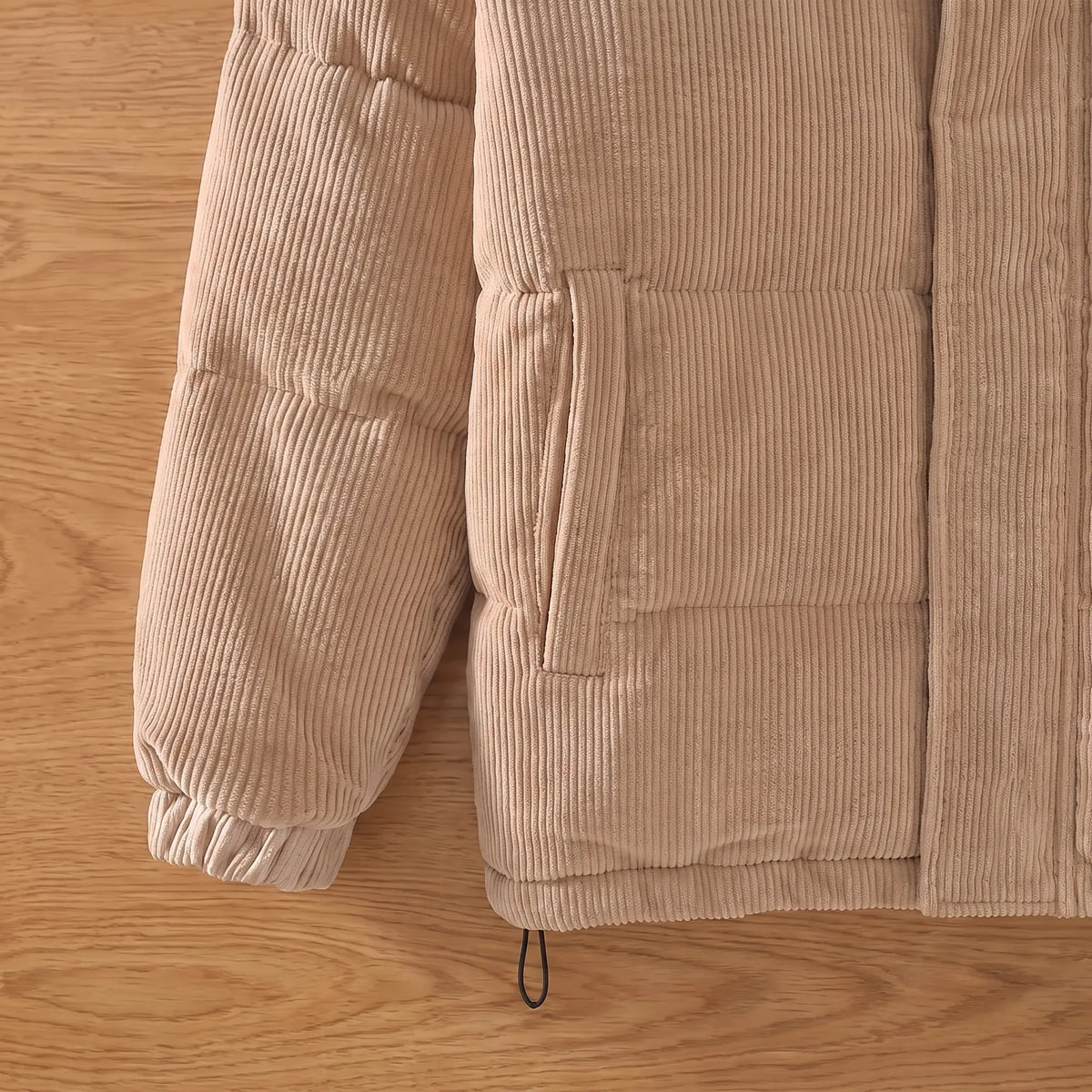 Close up of the welt pocket, quilted channels, hem toggle and cuff on the khaki corduroy puffer