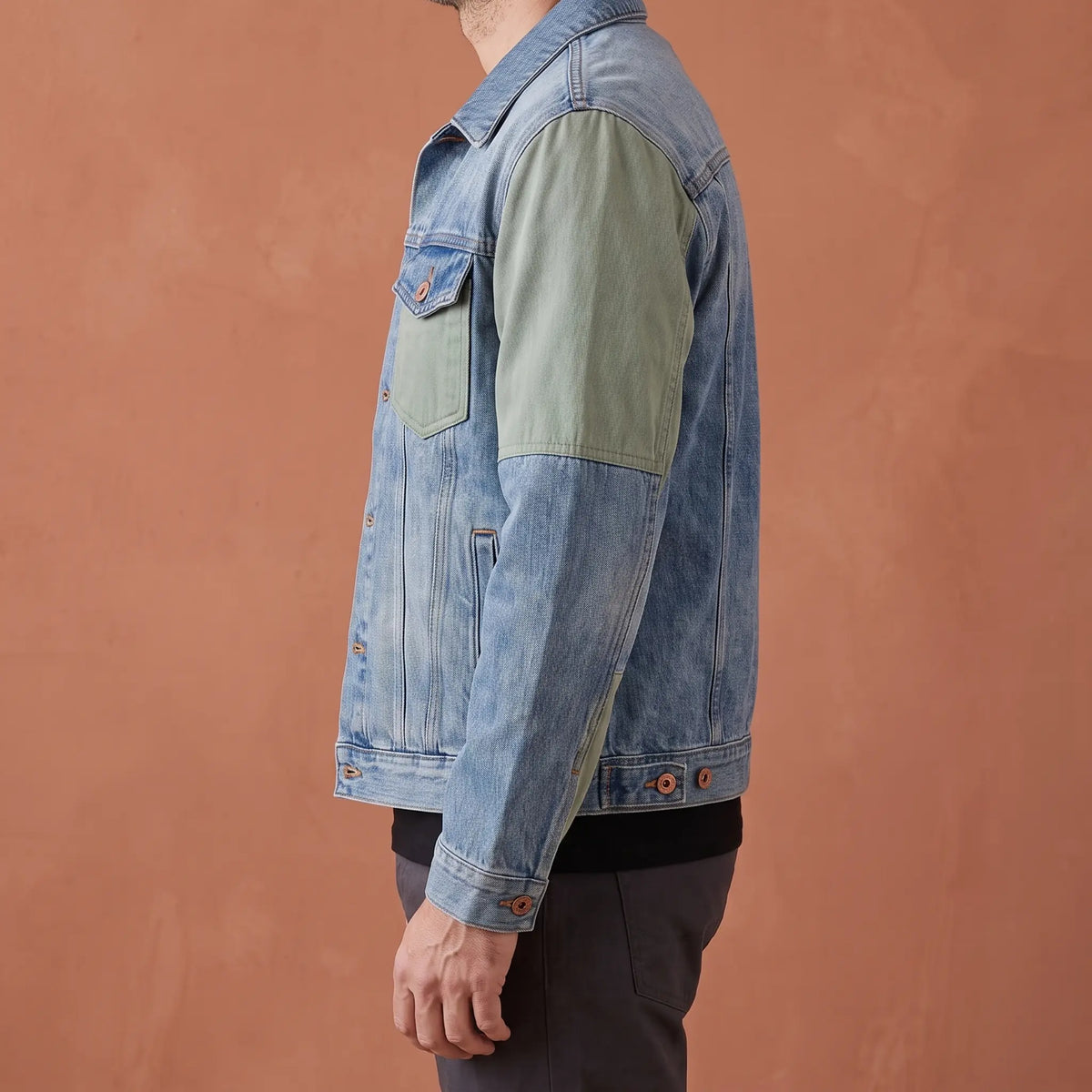 Side profile of the panelled denim jacket showing the sage sleeve panel and boxy shape