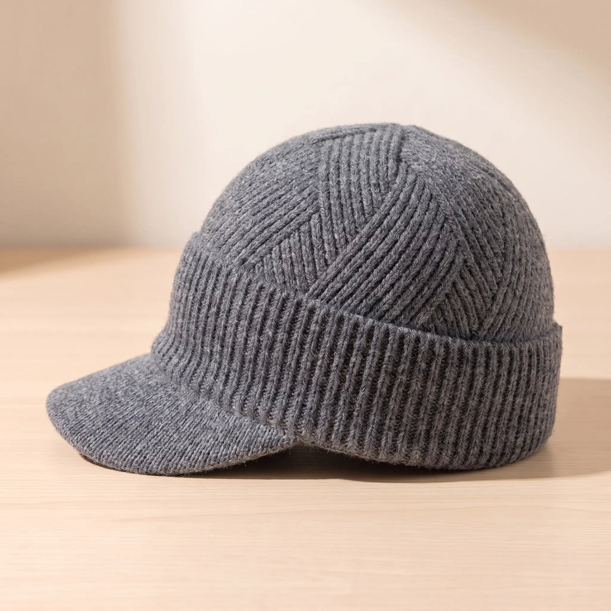 Side view of grey peaked knit beanie showing short knitted peak and cuff