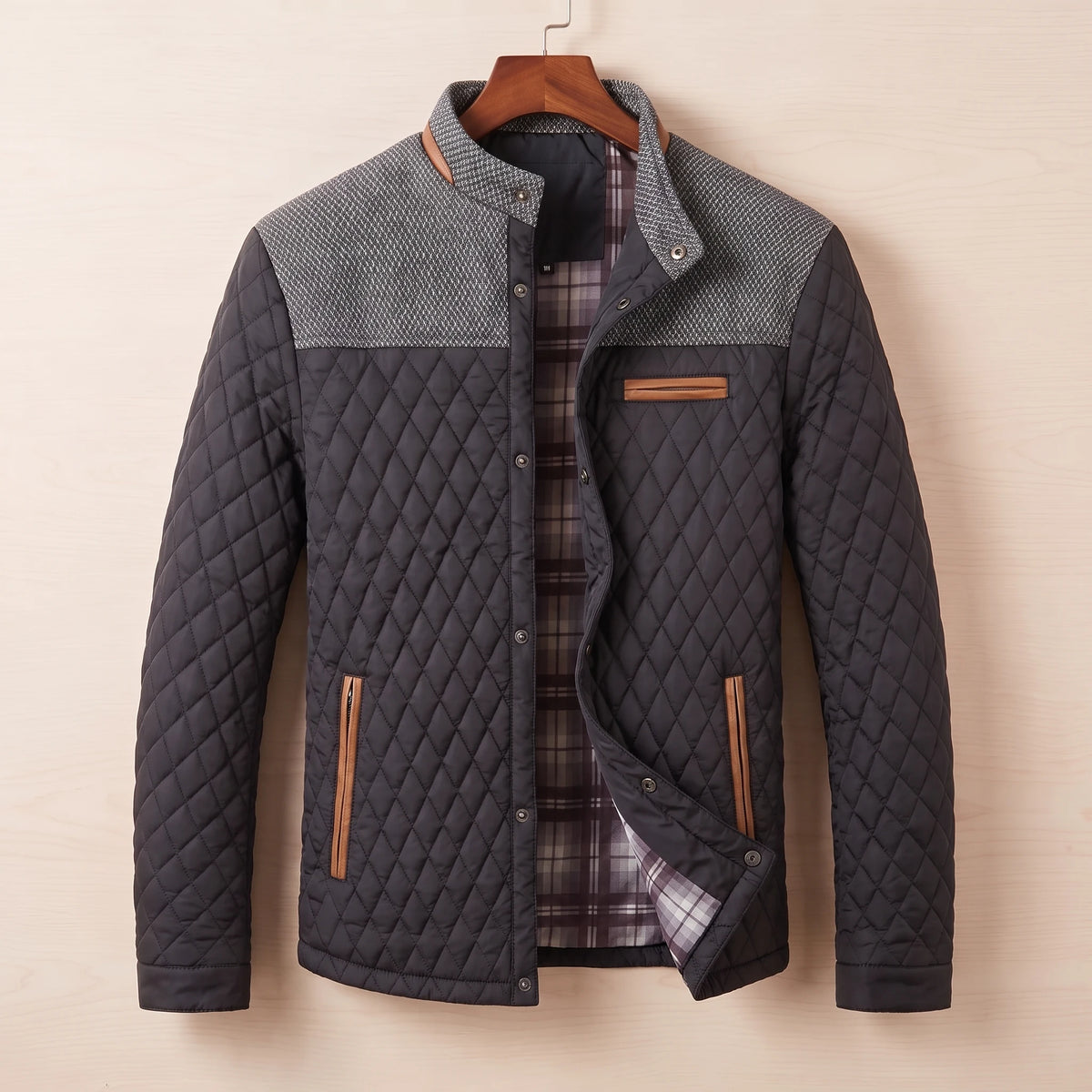 Black diamond quilted jacket with tweed shoulder yoke on a wooden hanger