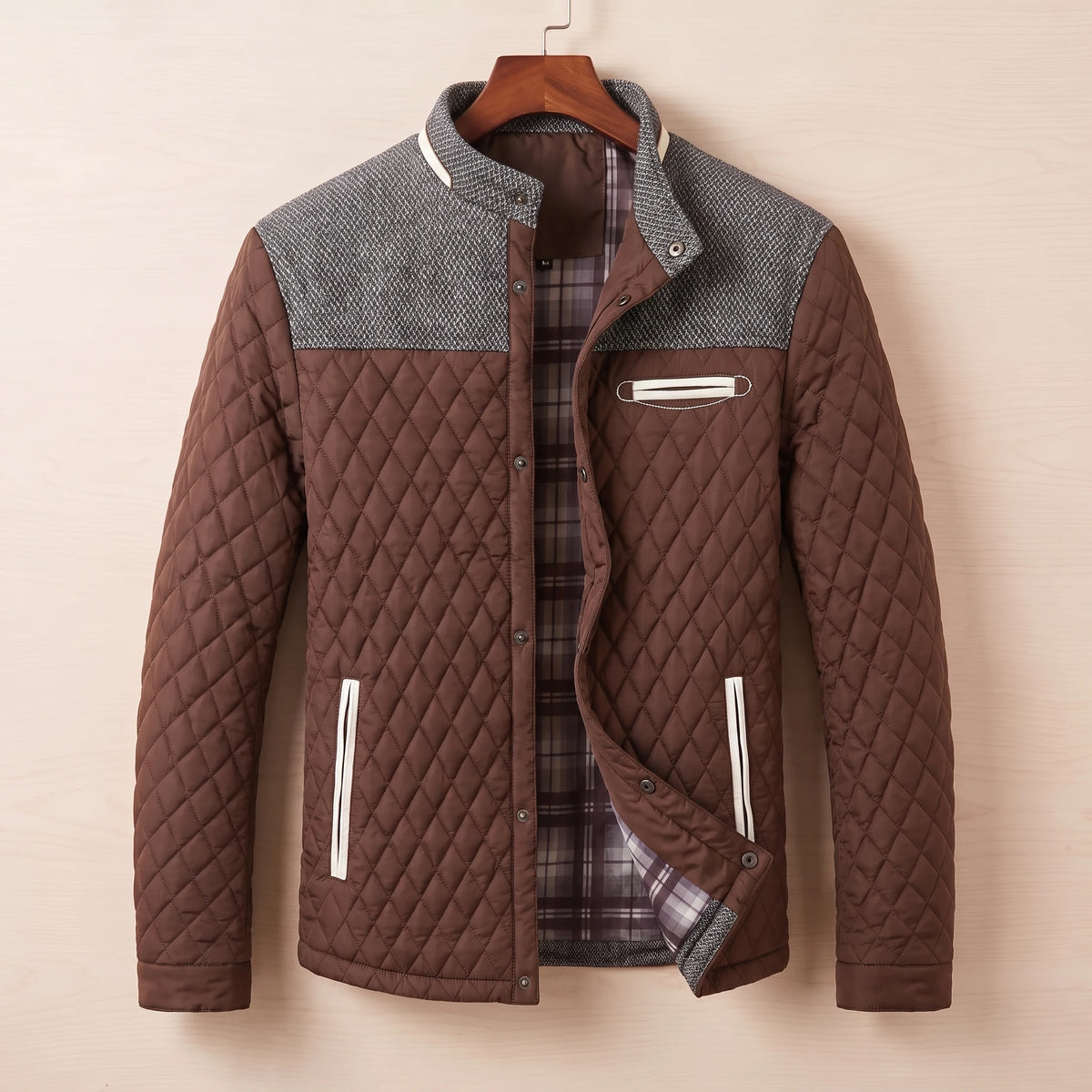 Brown diamond quilted jacket with tweed shoulder yoke on a wooden hanger