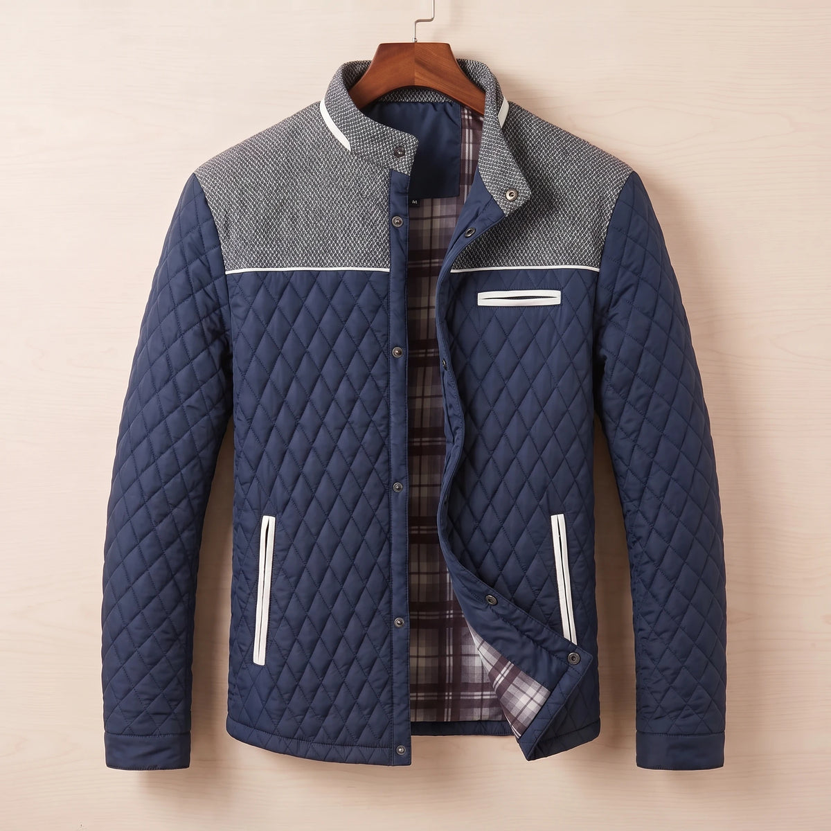 Navy blue diamond quilted jacket with tweed shoulder yoke on a wooden hanger