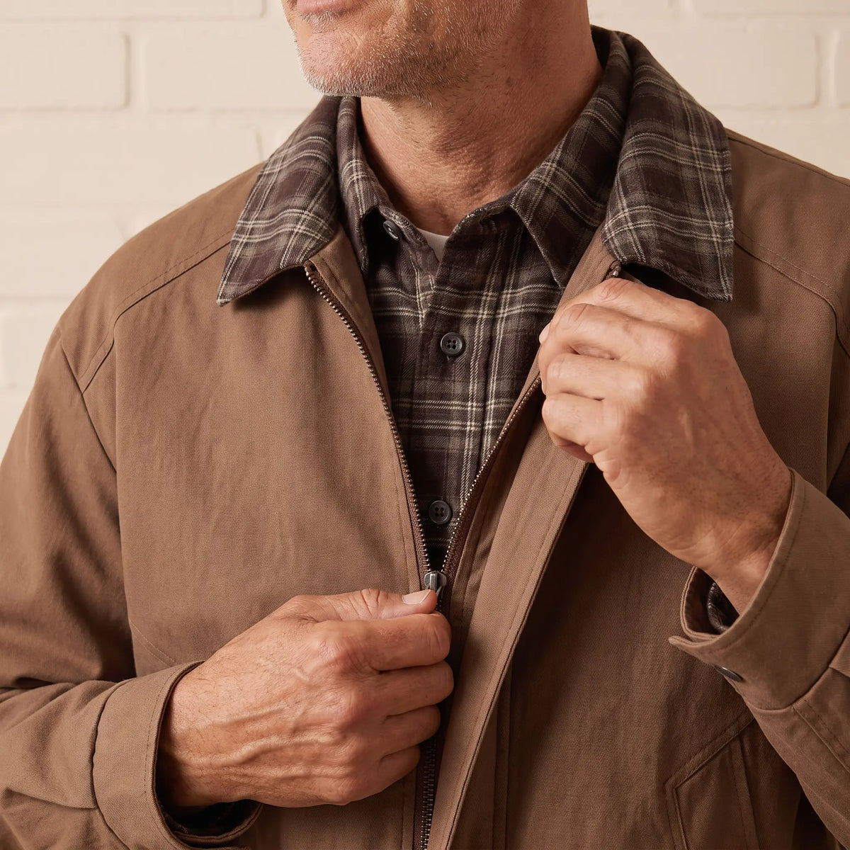 Man zipping up the PLAID PLACKET JACKET in brown