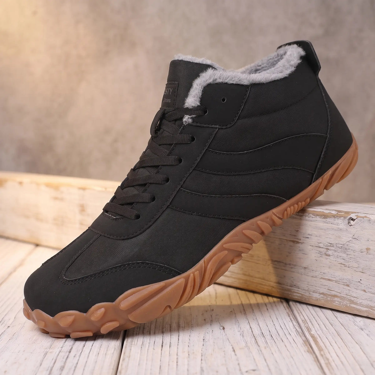 Men's black plush lined lace-up winter boot with gum tread sole on a pine ledge