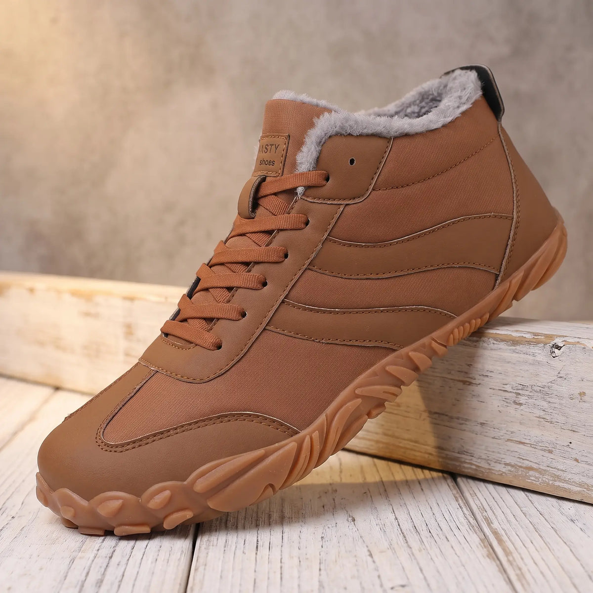 Men's brown plush lined lace-up winter boot with gum tread sole on a pine ledge