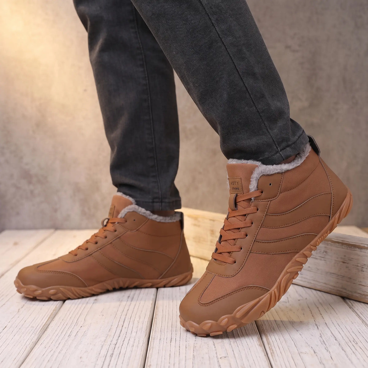 Man wearing brown plush collar winter boots with grey jeans