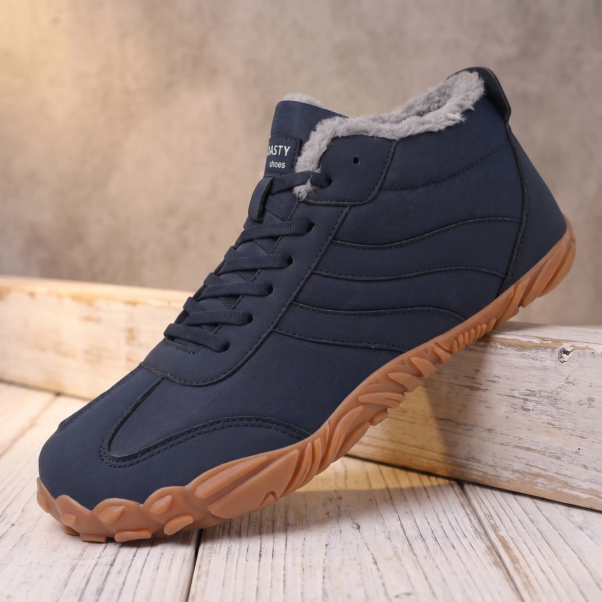 Men's navy blue plush lined lace-up winter boot with gum tread sole on a pine ledge