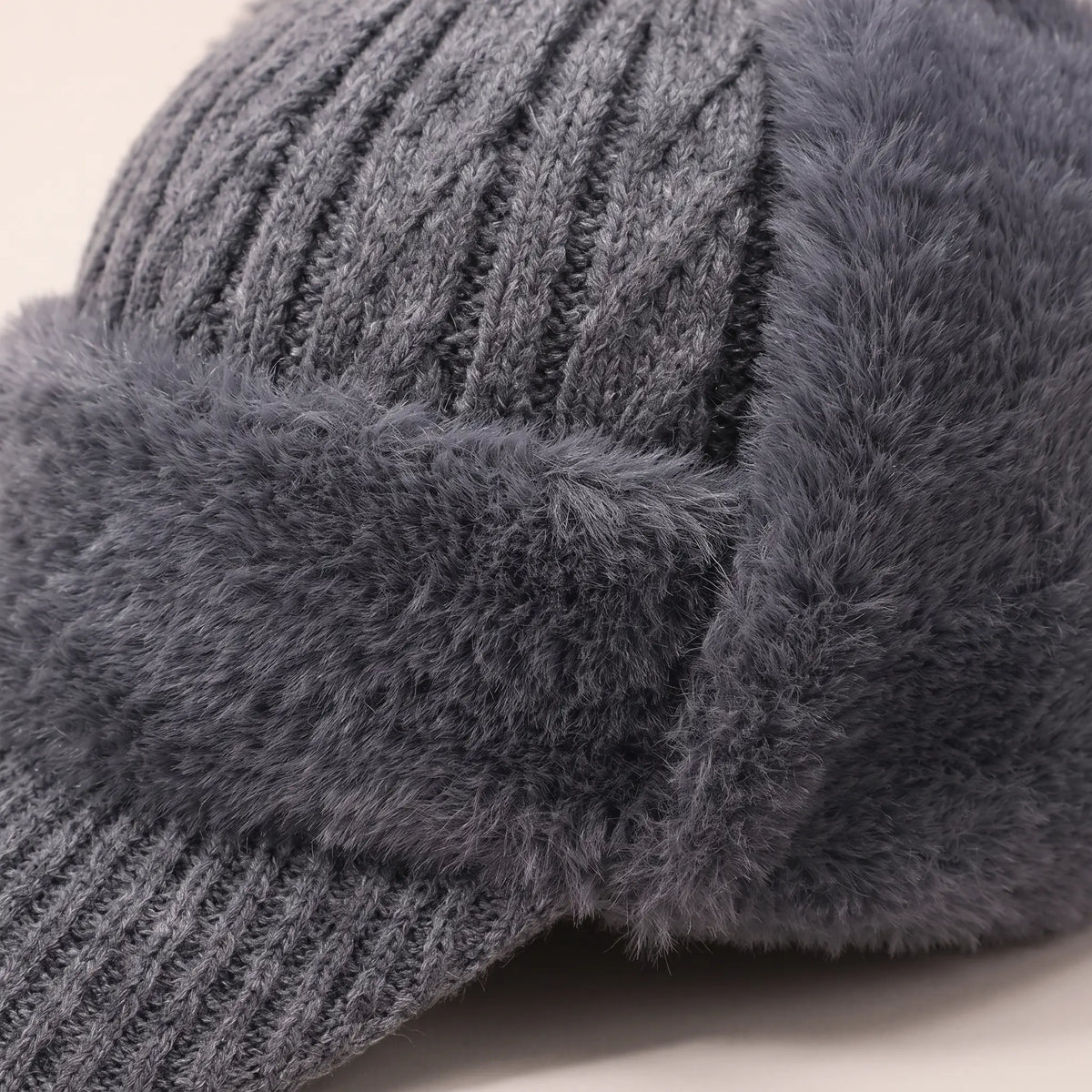 Close-up of grey earflap beanie cable knit crown meeting the soft plush band