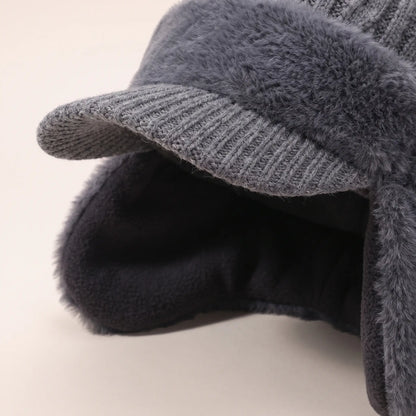 Close-up of grey earflap beanie showing knitted peak and dark fleece lining inside the ear flaps
