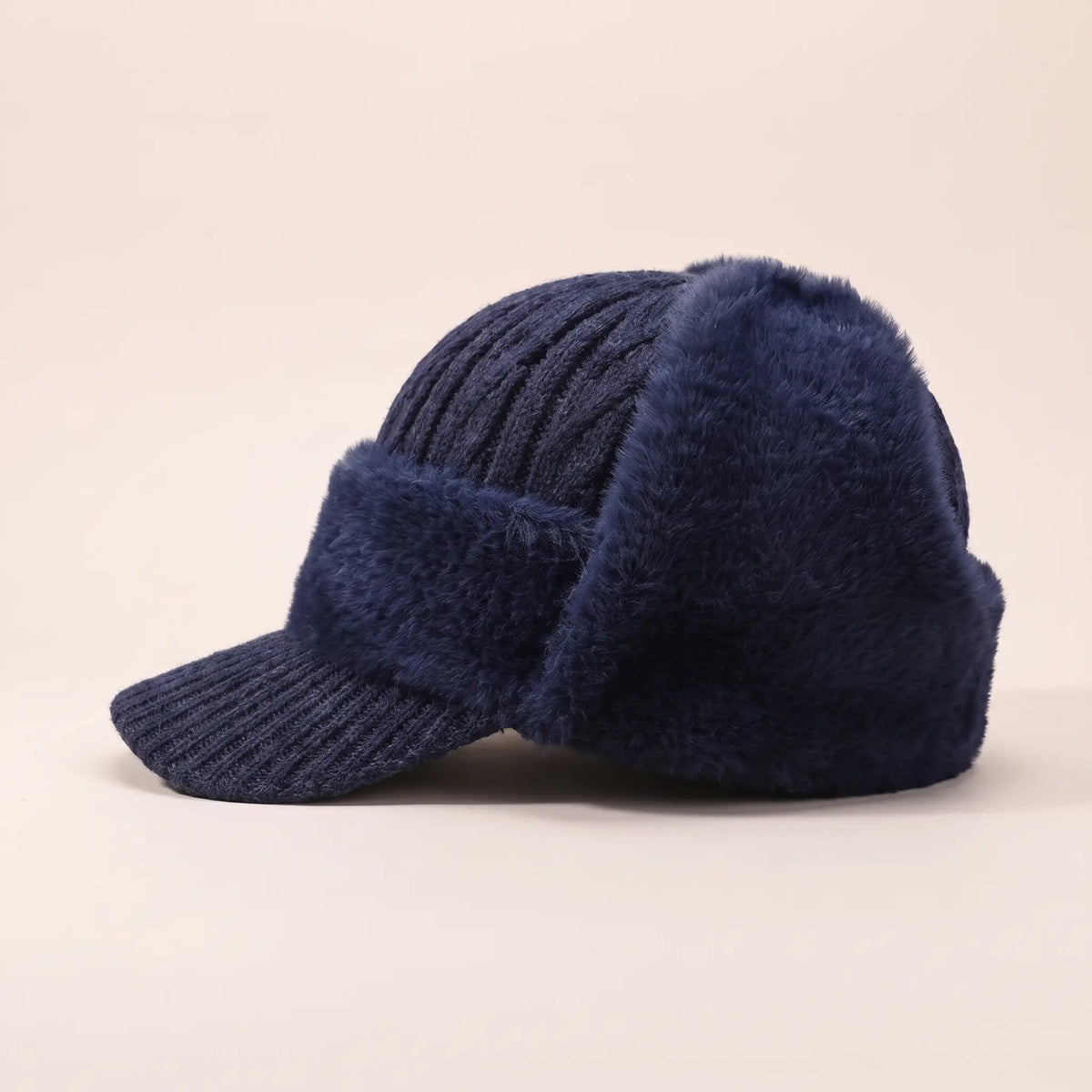 Men's navy blue plush earflap beanie with cable knit crown, short knitted peak and fleece-lined ear flaps, side view