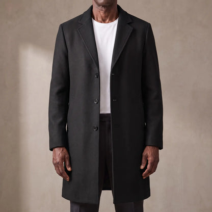Black long wool overcoat with quilted lining worn open over a white tee