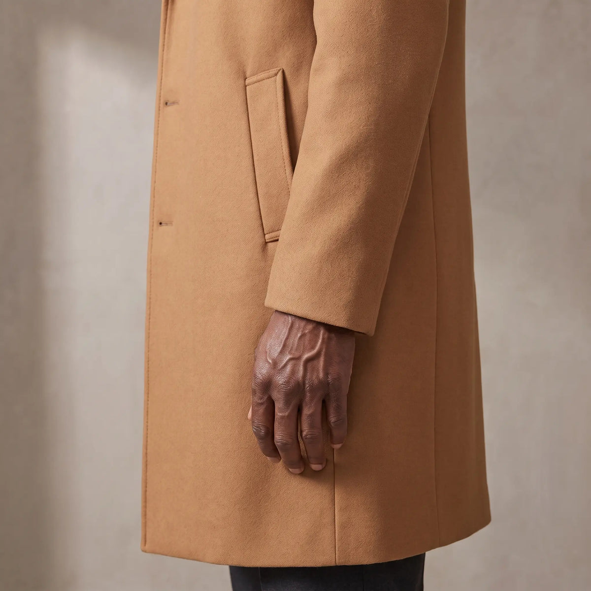 Close up of the sleeve cuff, hip welt pocket and hem of the wool overcoat