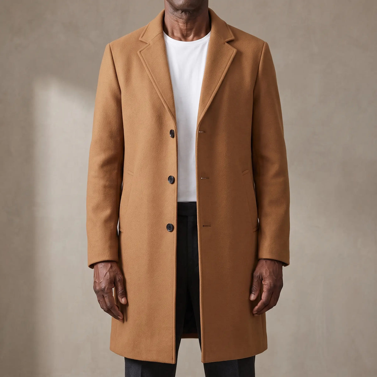 Tan long wool overcoat with quilted lining worn open over a white tee