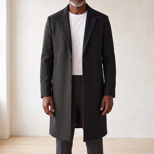 Black knee-length men's overcoat with two-button front and quilted lining, worn open over a white tee