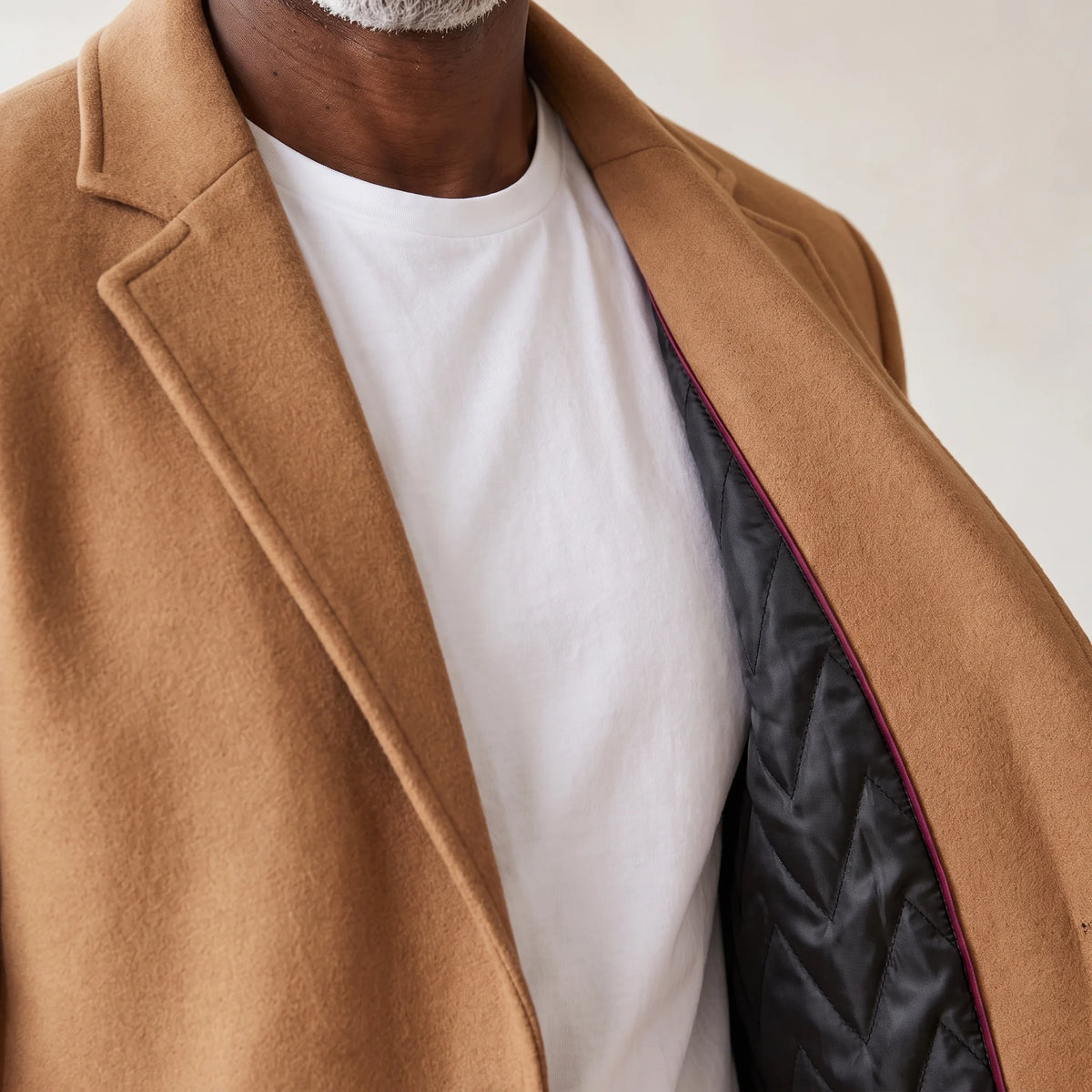 Close up of the notch lapel on the tan overcoat with the quilted lining showing at the front edge