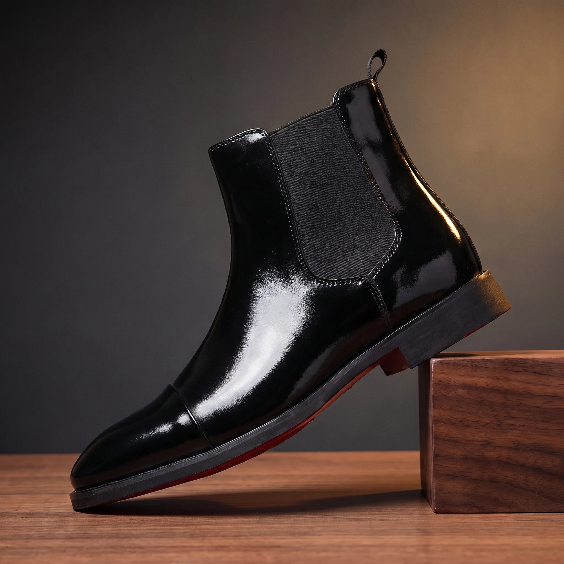 RED SOLE BOOTS in glossy black patent, red-sole Chelsea boot, pedestal hero