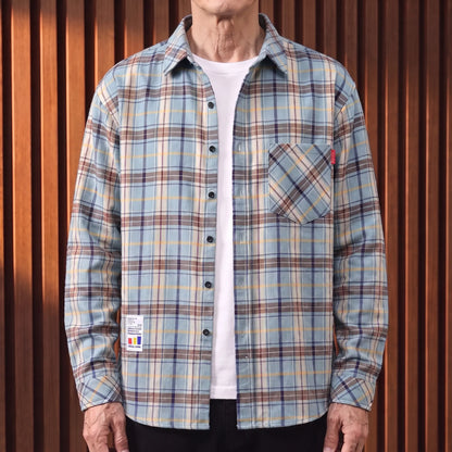 Blue plaid brushed flannel shirt worn open over a white tee by an older man