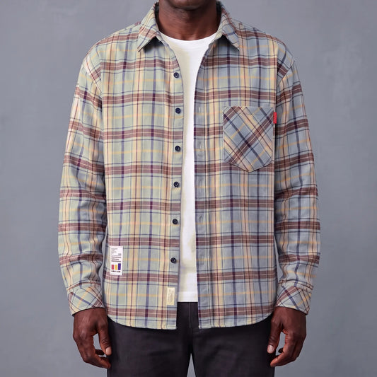 Green plaid brushed flannel shirt worn open over a white tee by an older man