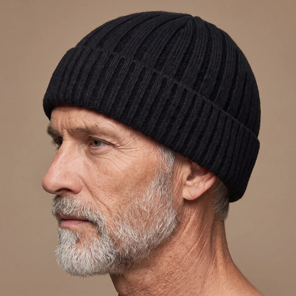 Ribbed docker beanie in black worn side profile by an older man