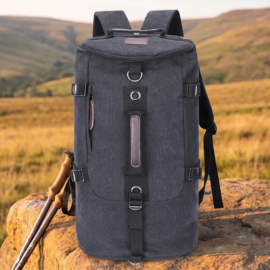 Ridge canvas rucksack in black, a roomy drum-shaped hiking backpack on a sandstone boulder