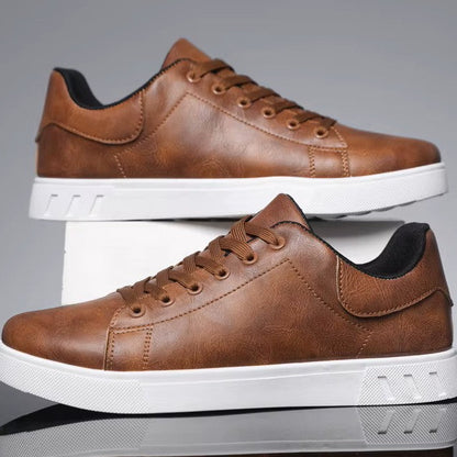 Pair of brown leather sneakers with white soles on a reflective surface.