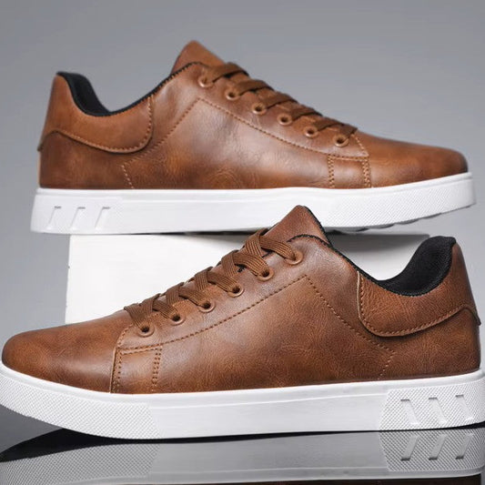 Pair of brown leather sneakers with white soles on a reflective surface.