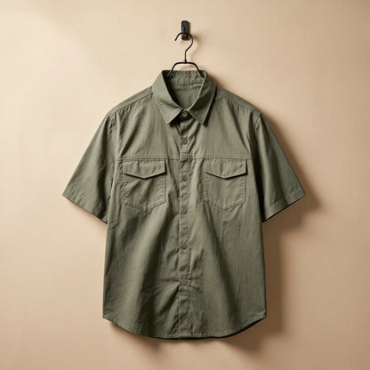 Olive green short sleeve utility shirt on a black hanger against a sand plaster wall