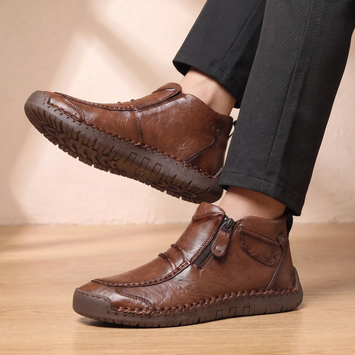Man seated wearing both SIDE ZIP BOOTS with dark trousers, ankles crossed