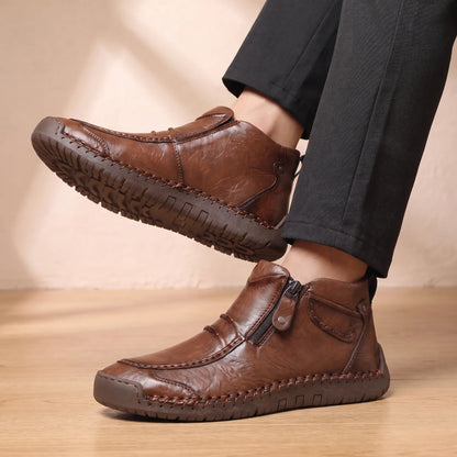 Man seated wearing both SIDE ZIP BOOTS with dark trousers, ankles crossed