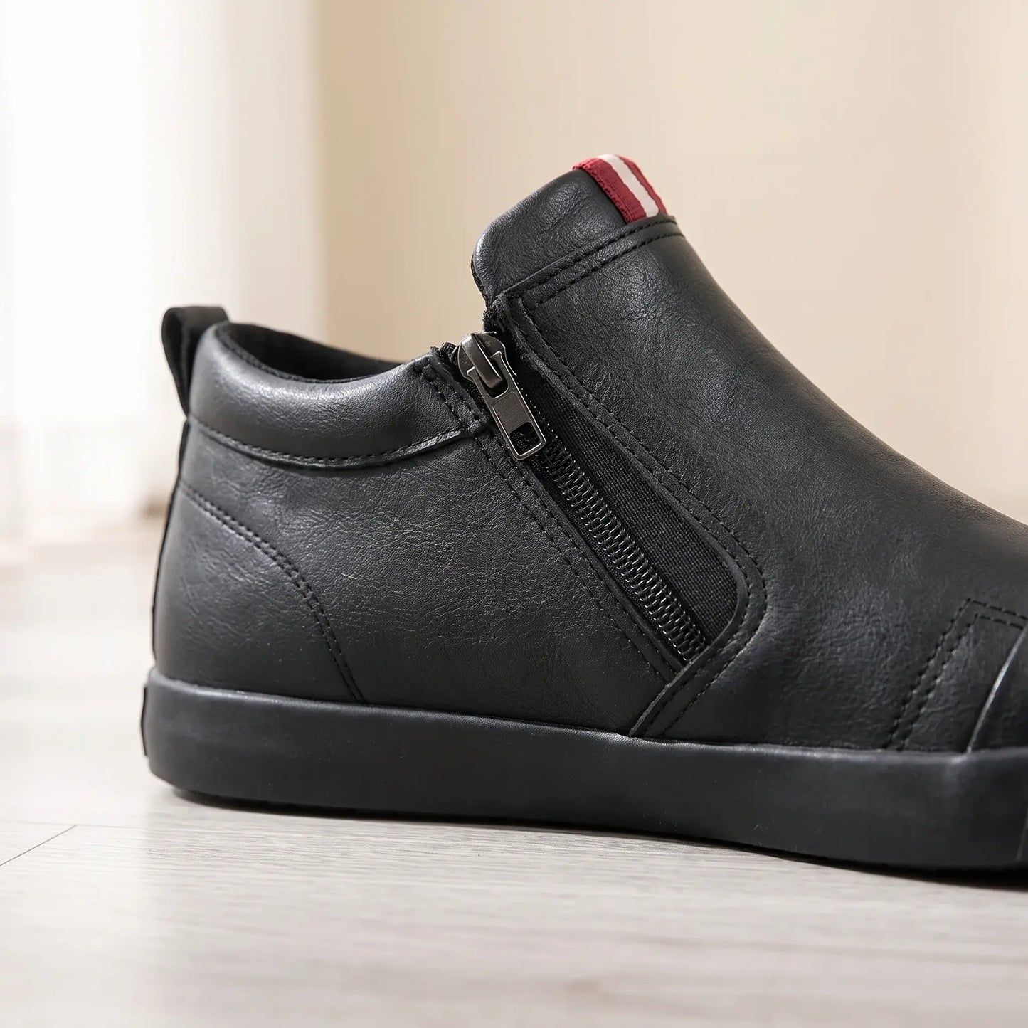 Close up of the side zip stretch panel and red and white tab on black slip on shoes
