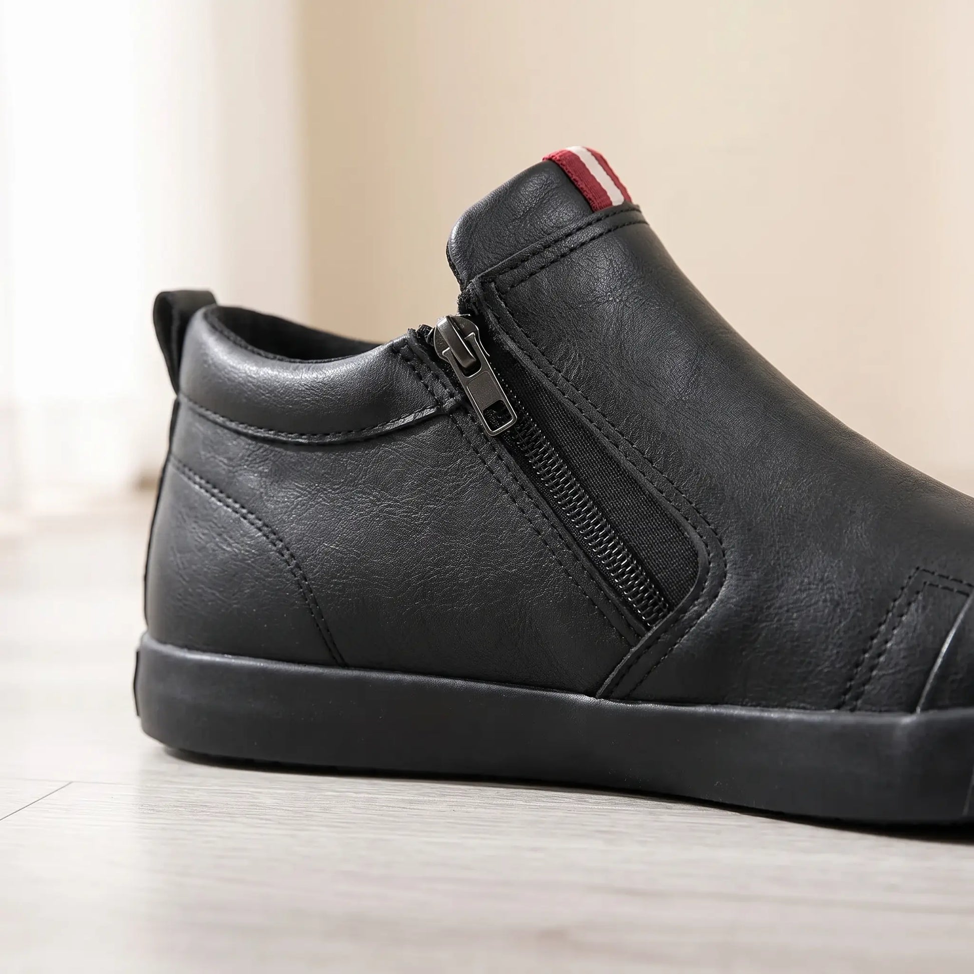 Close up of the side zip stretch panel and red and white tab on black slip on shoes