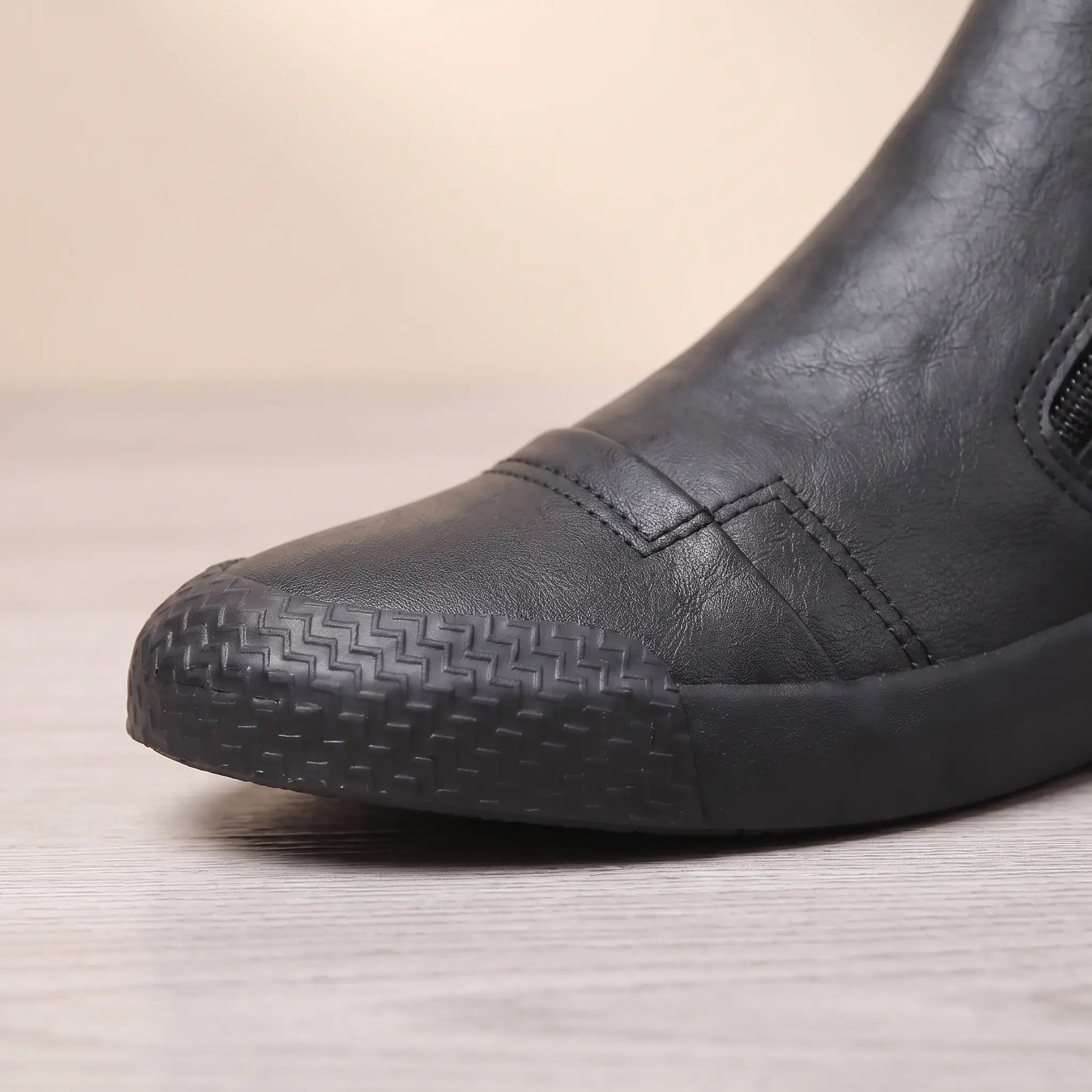Close up of the textured rubber toe guard on black side zip slip on shoes