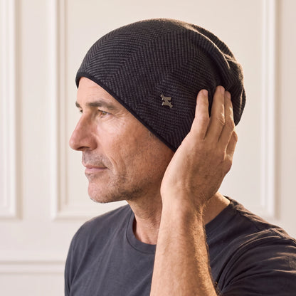 Man settling the black slouch knit beanie over his ear, fleece lined herringbone beanie worn