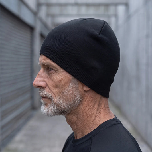 Smooth knit beanie in black worn side profile by an older man