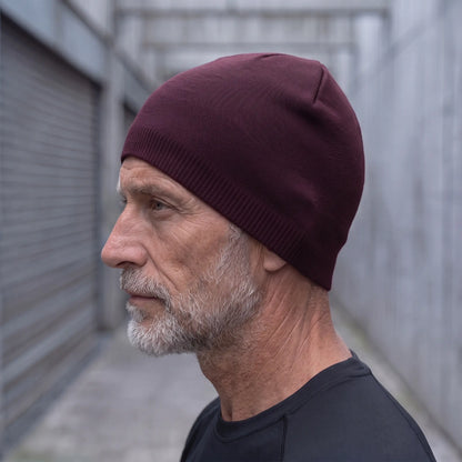 Smooth knit beanie in burgundy worn side profile by an older man