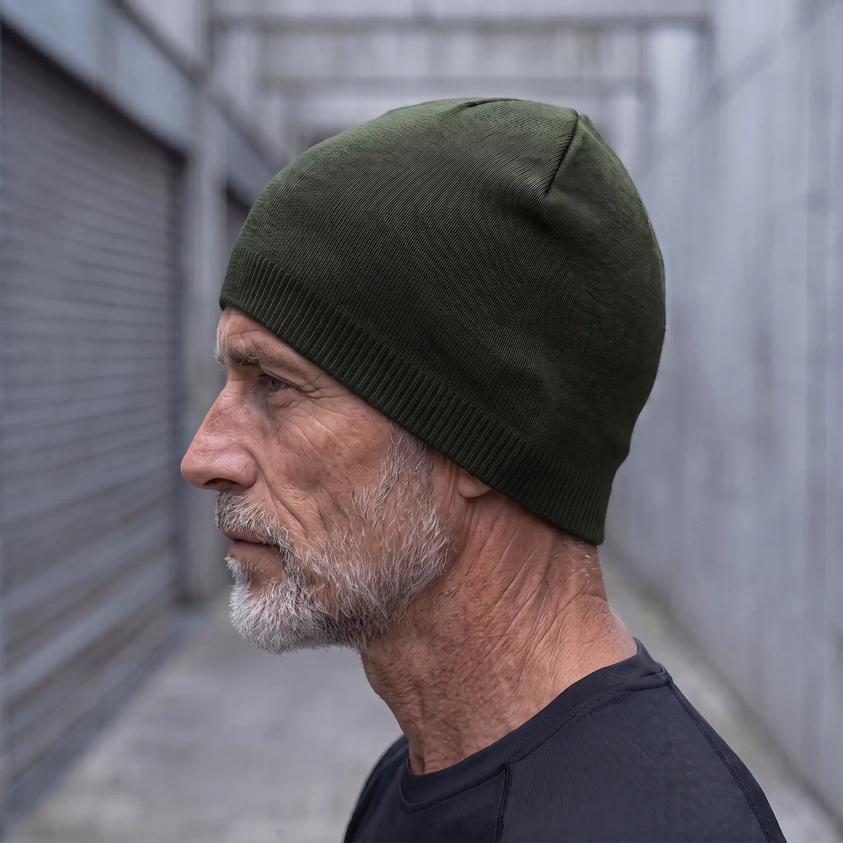 Smooth knit beanie in green worn side profile by an older man