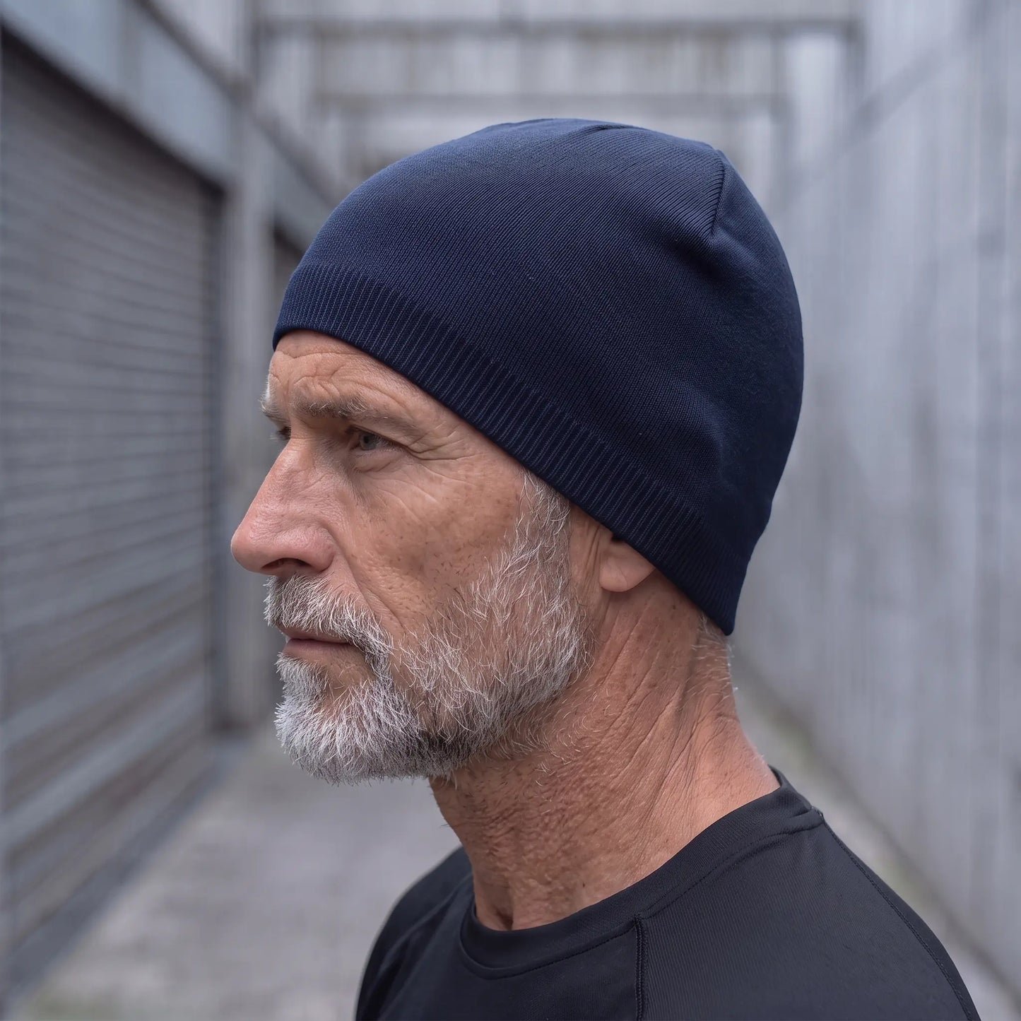 Smooth knit beanie in navy worn side profile by an older man