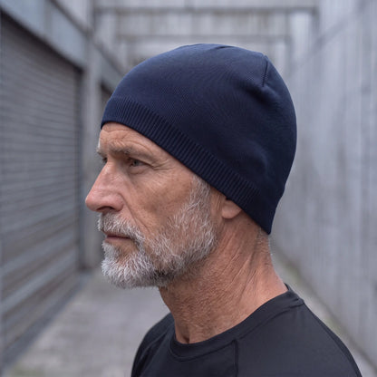 Smooth knit beanie in navy worn side profile by an older man