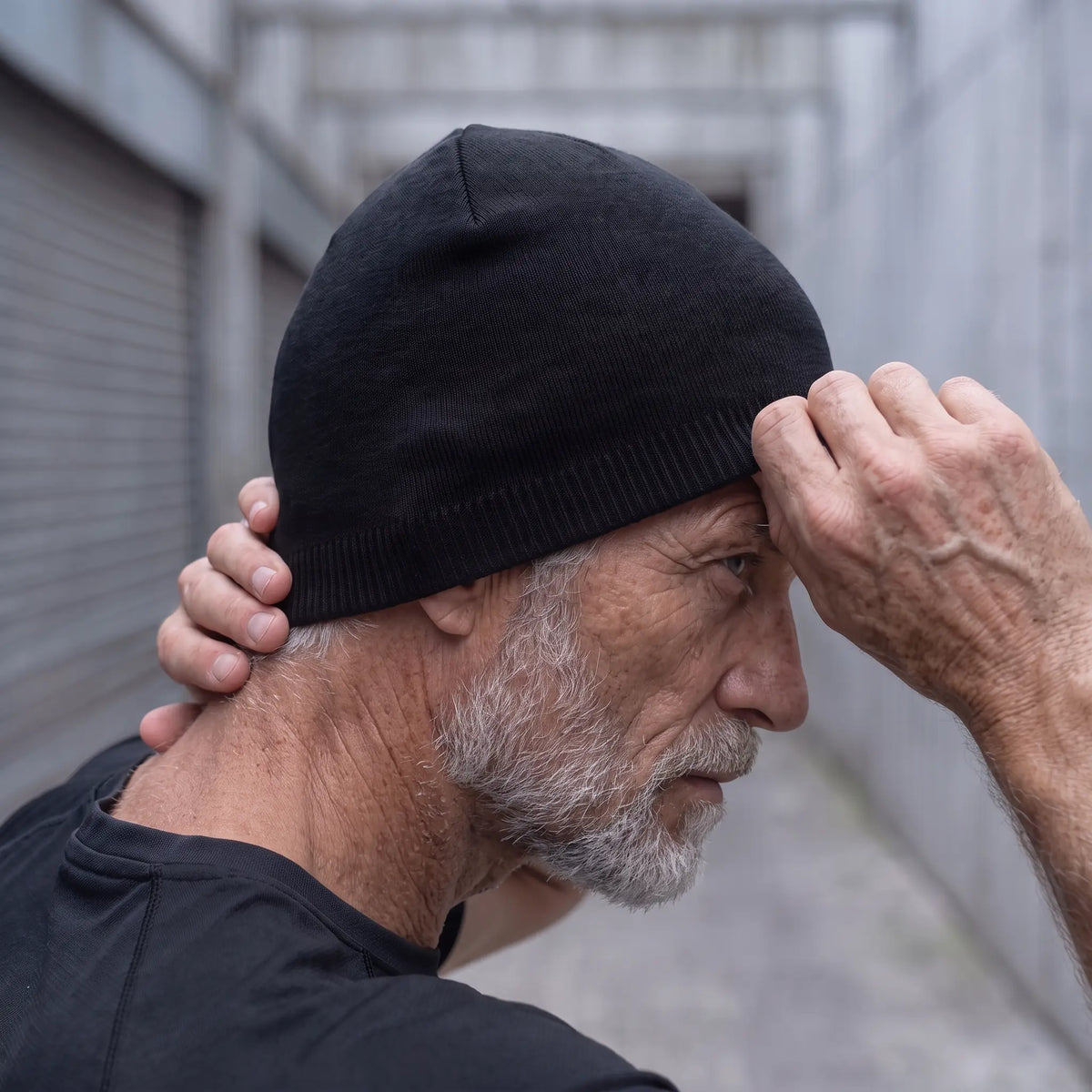 Older man tugging the smooth knit beanie down over his ear