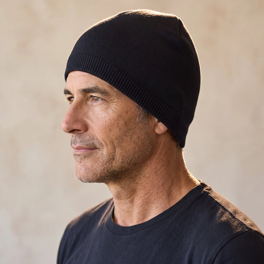 Smooth knit beanie in black, close fit pulled down over the ears, men's winter beanie shown in side profile