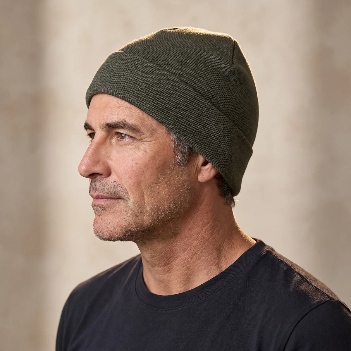 Smooth knit beanie in green, close fit pulled down over the ears, men's winter beanie shown in side profile