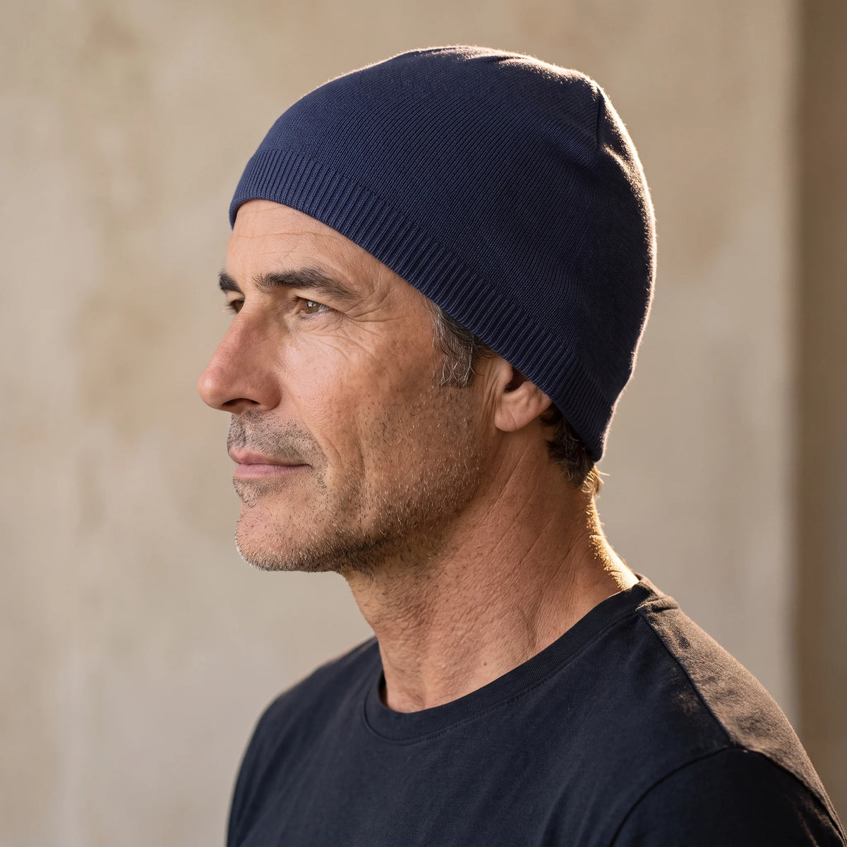 Smooth knit beanie in navy, close fit pulled down over the ears, men's winter beanie shown in side profile