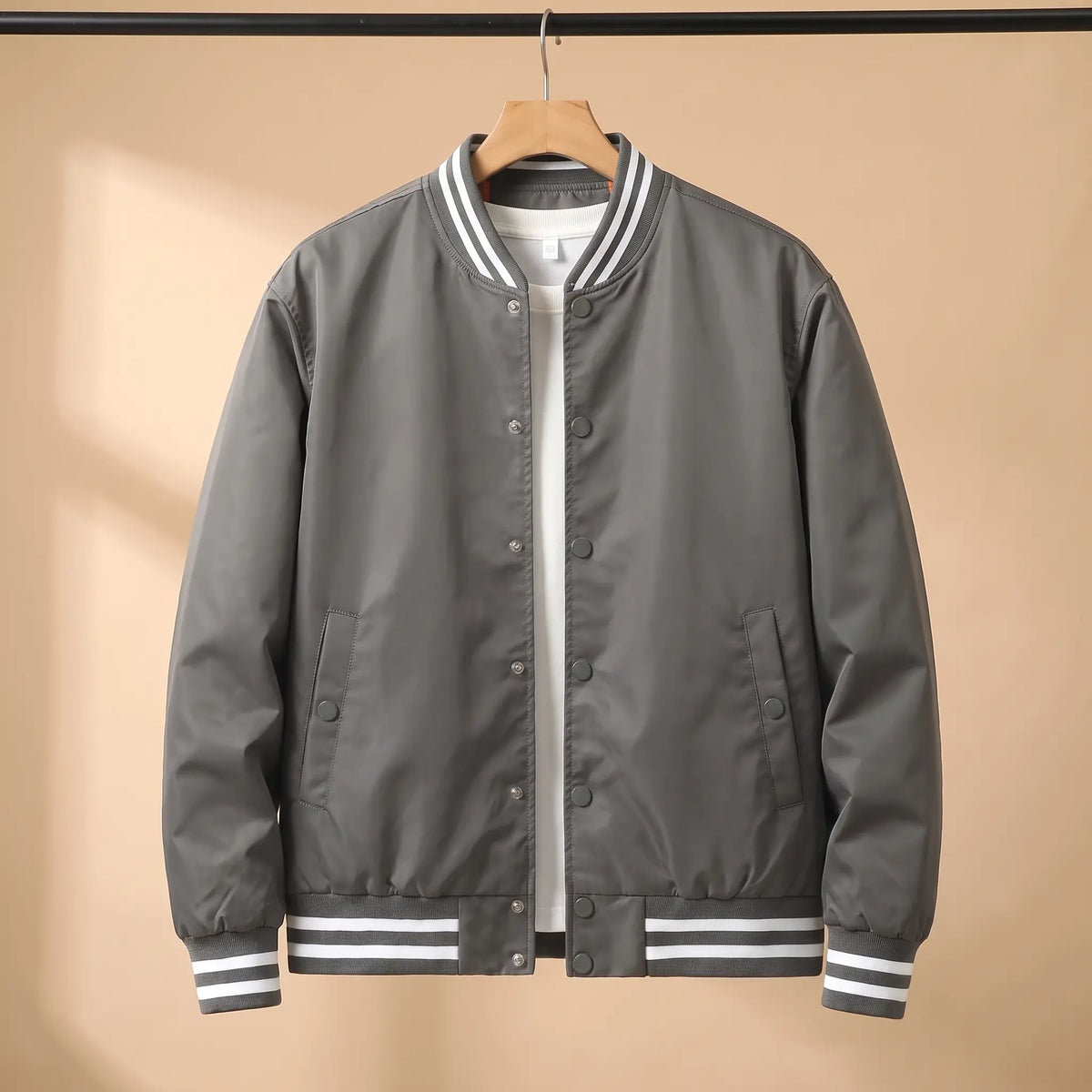 Men's grey snap-front baseball bomber jacket with white-striped rib collar, cuffs and hem on a wooden hanger