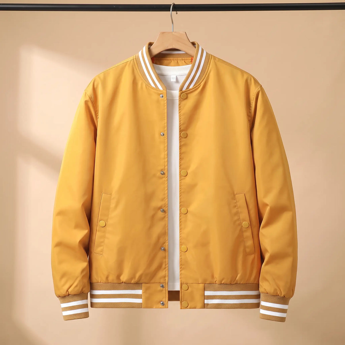Men's yellow snap-front baseball bomber jacket with white-striped rib collar, cuffs and hem on a wooden hanger
