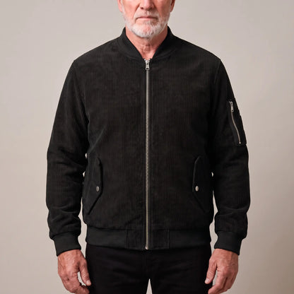 Men's black corduroy bomber jacket with ribbed collar and snap-flap pockets, worn zipped